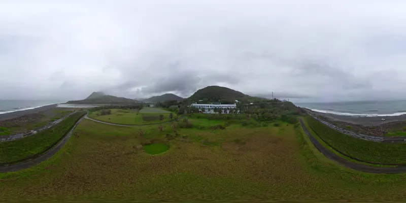 360° 空拍環景：草坪上空望向建築與海岸